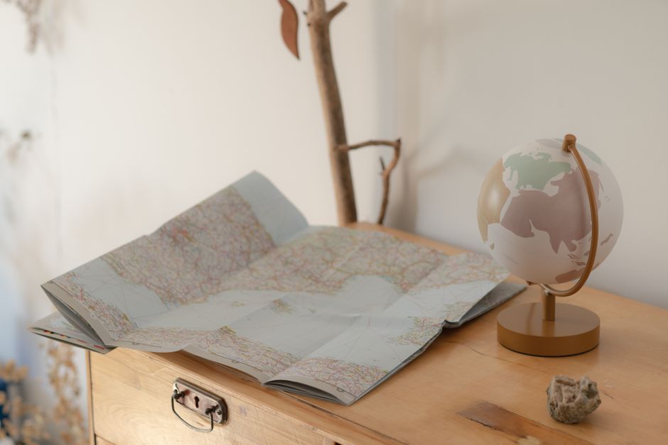 Cozy setting of a vintage map and globe on a wooden table, symbolizing travel exploration.